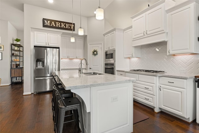 8903 Purdy Crescent Trl, Richmond, TX 77406 - kitchen featuring stainless steel appliances, dark wood-style floors, white cabinetry, a kitchen breakfast bar, and light stone countertops