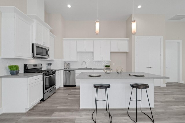 2504 W Tidwell Rd Unit C, Houston, TX 77091 - kitchen with appliances with stainless steel finishes, a breakfast bar, white cabinets, a kitchen island, and recessed lighting