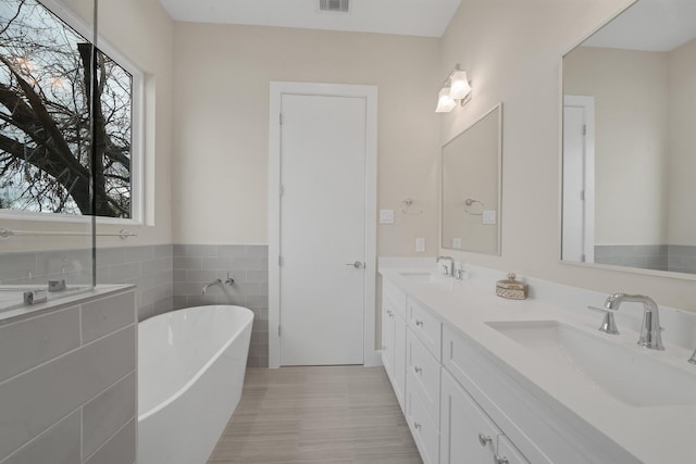 2504 W Tidwell Rd Unit C, Houston, TX 77091 - full bath with plenty of natural light, a soaking tub, double vanity, tile walls, and wainscoting