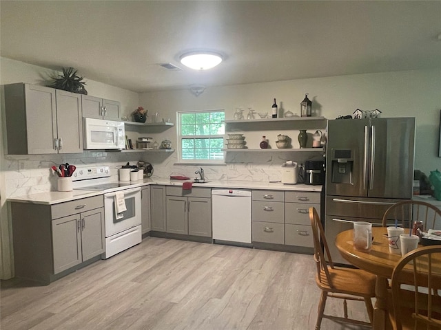 36218 Post Oak Cir, Magnolia, TX 77355 - kitchen featuring white appliances, open shelves, gray cabinetry, light wood-style floors, and backsplash