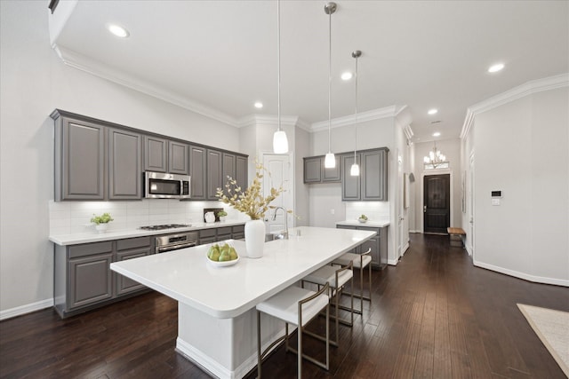 13223 Parkway Spring Dr, Houston, TX 77077 - kitchen featuring appliances with stainless steel finishes, gray cabinetry, crown molding, decorative backsplash, and a kitchen island with sink