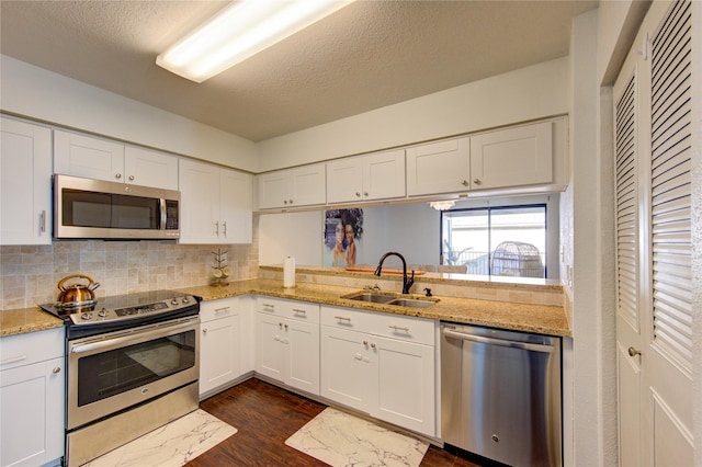 8100 Cambridge St Unit 114, Houston, TX 77054 - kitchen featuring appliances with stainless steel finishes, white cabinetry, dark wood finished floors, tasteful backsplash, and light stone counters