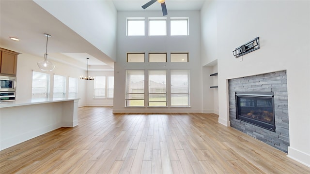 23604 Olive Creek Ln, New Caney, TX 77357 - unfurnished living room with ceiling fan, light wood-style floors, a fireplace, a chandelier, and built in shelves