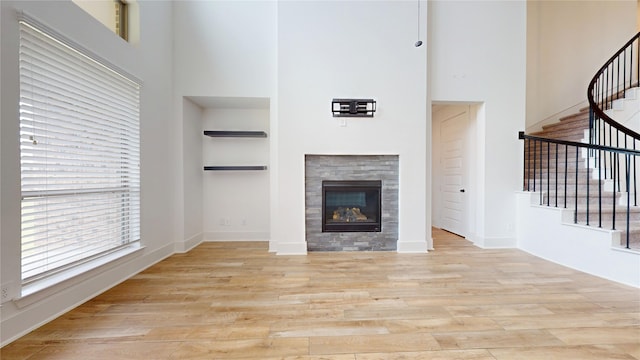 23604 Olive Creek Ln, New Caney, TX 77357 - unfurnished living room with a high ceiling, built in shelves, stairway, wood finished floors, and a tile fireplace
