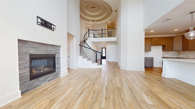 23604 Olive Creek Ln, New Caney, TX 77357 - unfurnished living room with light wood-type flooring, stairway, a high ceiling, a fireplace, and recessed lighting