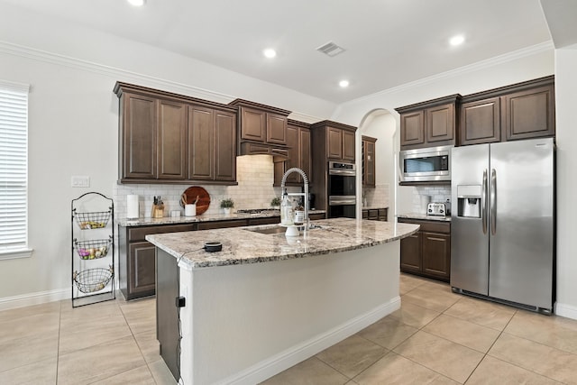 15415 Wildpoint Dr, Cypress, TX 77429 - kitchen with appliances with stainless steel finishes, dark brown cabinetry, light tile patterned floors, tasteful backsplash, and ornamental molding