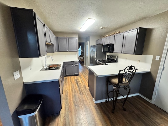 2702 Dovewood Ln, Spring, TX 77373 - kitchen with appliances with stainless steel finishes, a peninsula, light wood finished floors, a breakfast bar area, and a textured ceiling
