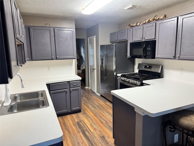 2702 Dovewood Ln, Spring, TX 77373 - kitchen with appliances with stainless steel finishes, a peninsula, wood finished floors, light countertops, and a textured ceiling
