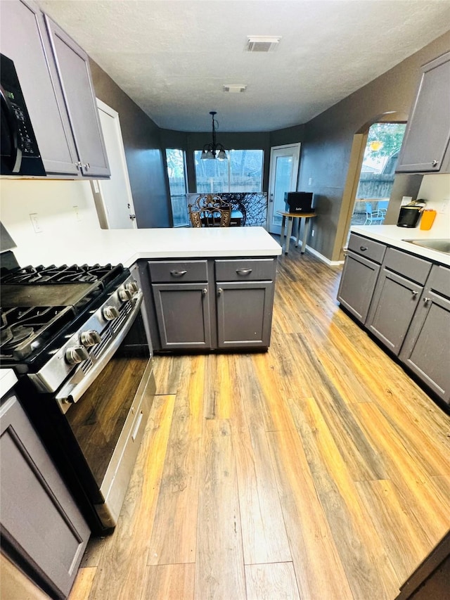 2702 Dovewood Ln, Spring, TX 77373 - kitchen with stainless steel range with gas stovetop, a peninsula, gray cabinetry, and light wood-style floors