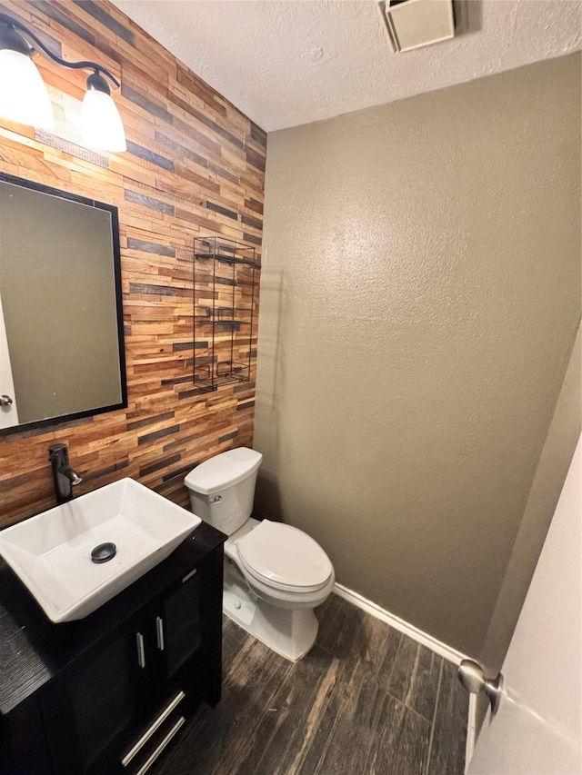 2702 Dovewood Ln, Spring, TX 77373 - half bath with wood walls, wood finished floors, vanity, an accent wall, and a textured ceiling