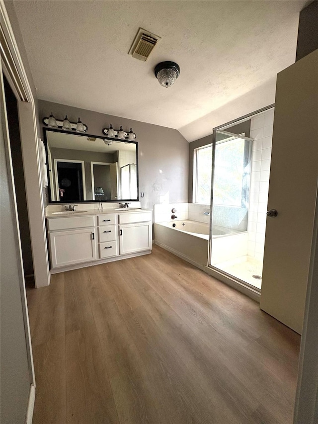 2702 Dovewood Ln, Spring, TX 77373 - bathroom featuring wood finished floors, lofted ceiling, double vanity, a jetted tub, and a stall shower