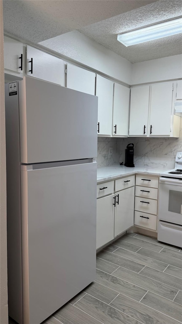 12922 Wirevine Ln, Houston, TX 77072 - kitchen with white appliances, backsplash, white cabinetry, light countertops, and a textured ceiling