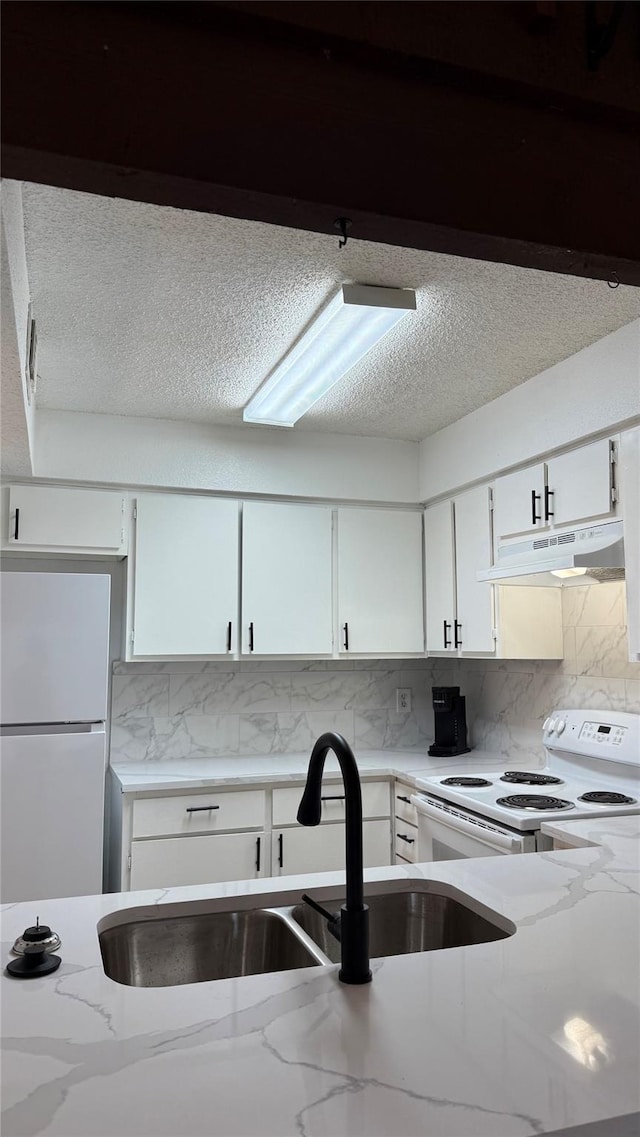 12922 Wirevine Ln, Houston, TX 77072 - kitchen featuring under cabinet range hood, white appliances, tasteful backsplash, white cabinets, and a textured ceiling