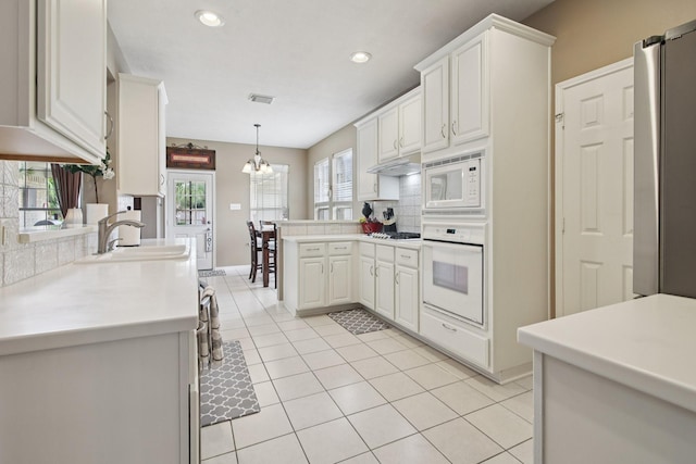 12103 Via San Rocco Ct, Cypress, TX 77429 - kitchen with white appliances, backsplash, a peninsula, light tile patterned flooring, and recessed lighting