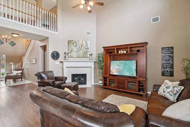 12103 Via San Rocco Ct, Cypress, TX 77429 - living room featuring a towering ceiling, a ceiling fan, wood finished floors, a tiled fireplace, and stairway