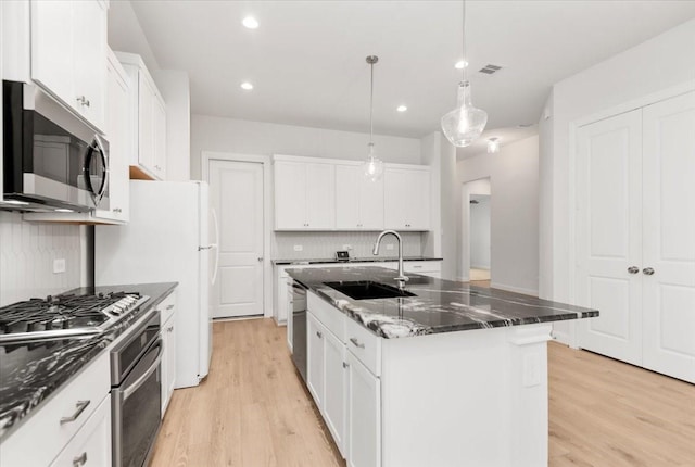 12831 Raemoir Dr, Humble, TX 77346 - kitchen with stainless steel appliances, light wood finished floors, an island with sink, white cabinetry, and recessed lighting