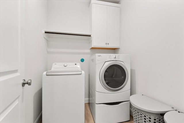 12831 Raemoir Dr, Humble, TX 77346 - laundry area featuring washing machine and clothes dryer, cabinet space, and light wood-style flooring