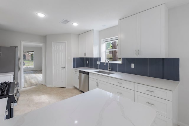 1815 Moston Dr, Spring, TX 77386 - kitchen with appliances with stainless steel finishes, white cabinetry, light stone counters, backsplash, and recessed lighting