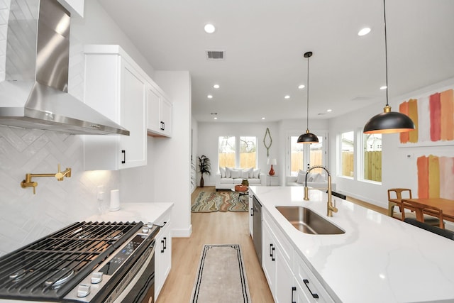 4415 Coke St Unit B, Houston, TX 77020 - kitchen featuring wall chimney exhaust hood, stainless steel gas stove, tasteful backsplash, light wood finished floors, and white cabinetry