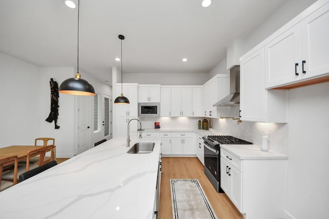 4415 Coke St Unit B, Houston, TX 77020 - kitchen featuring appliances with stainless steel finishes, wall chimney range hood, white cabinets, and recessed lighting