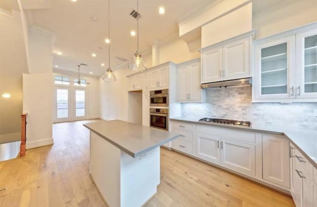 4041 Leeland St, Houston, TX 77023 - kitchen with appliances with stainless steel finishes, backsplash, light wood finished floors, a center island, and recessed lighting