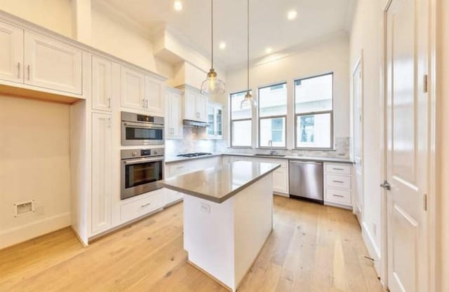 4041 Leeland St, Houston, TX 77023 - kitchen with dishwasher, light wood finished floors, white cabinets, ornamental molding, and a center island