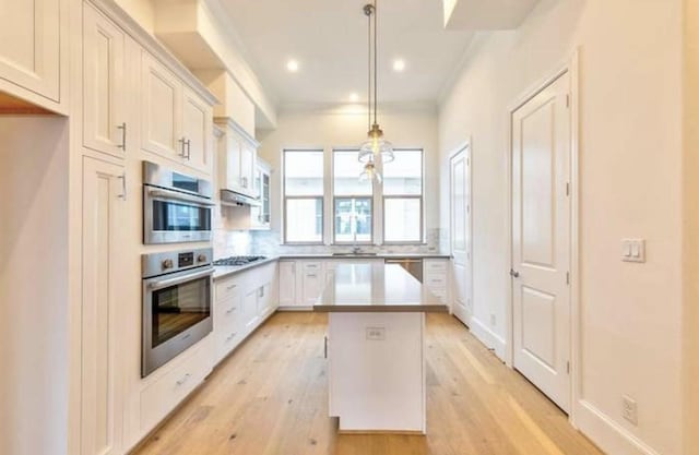 4041 Leeland St, Houston, TX 77023 - kitchen with appliances with stainless steel finishes, a center island, light wood-type flooring, white cabinetry, and recessed lighting