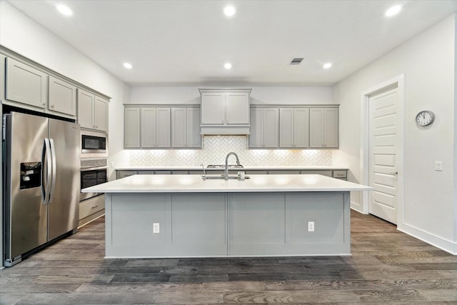 16630 Polletts Cove Ct, Humble, TX 77346 - kitchen with appliances with stainless steel finishes, gray cabinetry, a center island with sink, tasteful backsplash, and light countertops