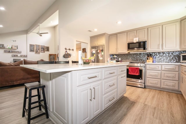6203 Wickwillow Ln, Alvin, TX 77511 - kitchen featuring stainless steel appliances, light wood-style floors, open floor plan, decorative backsplash, and light countertops