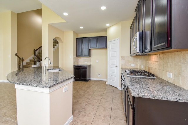 20315 Cypress Poll Dr, Cypress, TX 77433 - kitchen featuring appliances with stainless steel finishes, light tile patterned floors, arched walkways, light stone countertops, and decorative backsplash