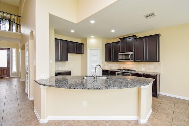 20315 Cypress Poll Dr, Cypress, TX 77433 - kitchen featuring stainless steel microwave, stone countertops, backsplash, arched walkways, and light tile patterned floors