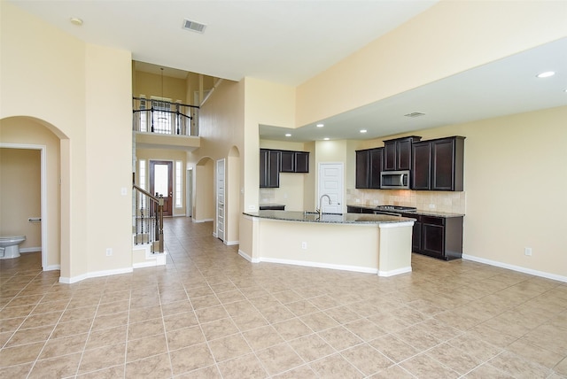 20315 Cypress Poll Dr, Cypress, TX 77433 - kitchen featuring stainless steel appliances, arched walkways, light tile patterned floors, light stone counters, and tasteful backsplash