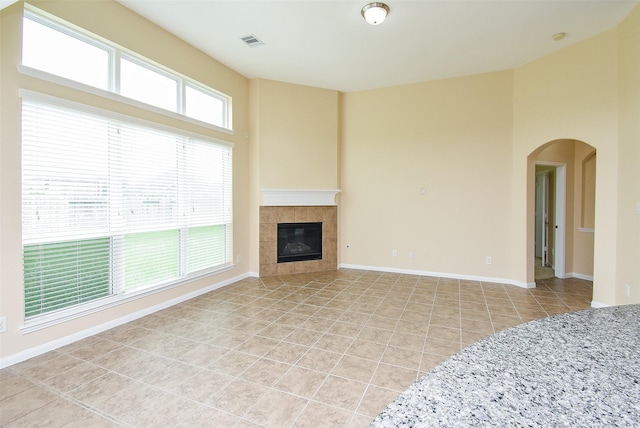 20315 Cypress Poll Dr, Cypress, TX 77433 - unfurnished living room featuring light tile patterned flooring, a tiled fireplace, arched walkways, and a towering ceiling