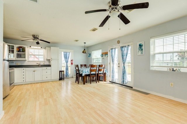 430 Jettyview Rd, Surfside Beach, TX 77541 - kitchen with a ceiling fan, dark countertops, light wood-style flooring, white cabinetry, and decorative light fixtures