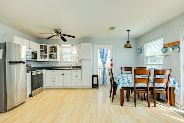 430 Jettyview Rd, Surfside Beach, TX 77541 - kitchen featuring stainless steel appliances, dark countertops, light wood finished floors, and white cabinets