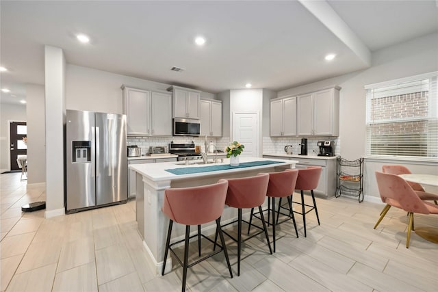 4427 Silvergrass Ln, Katy, TX 77493 - kitchen featuring appliances with stainless steel finishes, decorative backsplash, a center island with sink, a kitchen bar, and recessed lighting