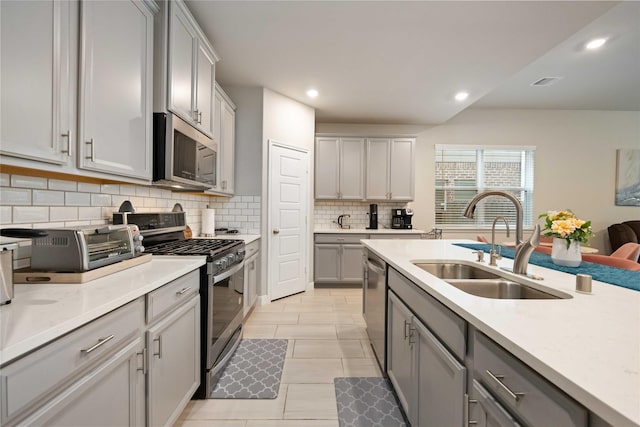 4427 Silvergrass Ln, Katy, TX 77493 - kitchen with stainless steel appliances, gray cabinetry, decorative backsplash, light countertops, and recessed lighting