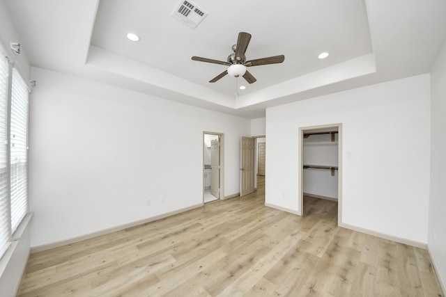 2119 Esther Dr, Houston, TX 77088 - unfurnished bedroom with a raised ceiling, light wood-type flooring, recessed lighting, a spacious closet, and ensuite bath