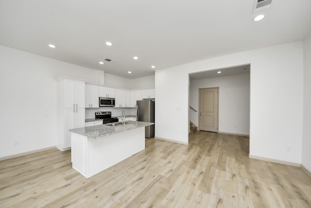 2119 Esther Dr, Houston, TX 77088 - kitchen featuring stainless steel appliances, a center island with sink, white cabinetry, light wood-style flooring, and recessed lighting