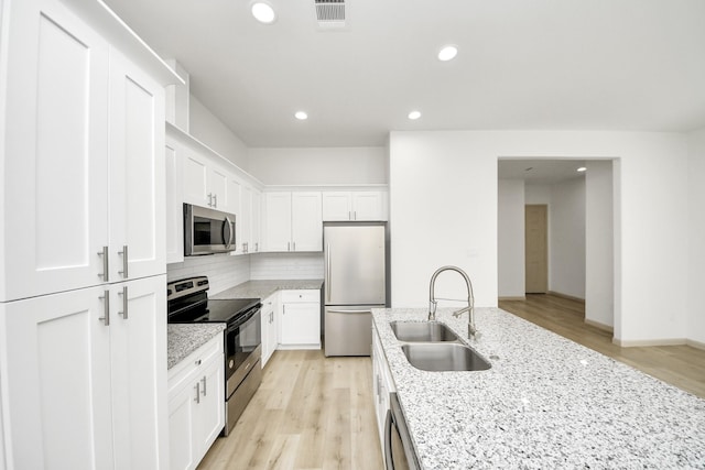 2119 Esther Dr, Houston, TX 77088 - kitchen with appliances with stainless steel finishes, backsplash, white cabinetry, recessed lighting, and light stone countertops