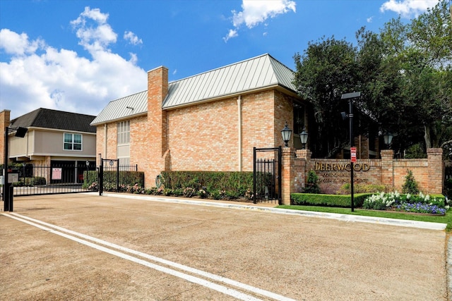 2238 S Piney Point Rd Unit 204, Houston, TX 77063 - view of side of property with a gate, brick siding, a metal roof, and a standing seam roof