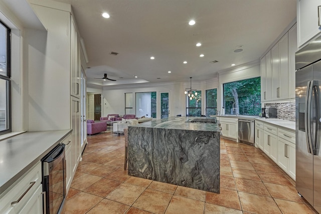 134 Trinity Oaks Ct, The Woodlands, TX 77381 - kitchen featuring beverage cooler, appliances with stainless steel finishes, crown molding, open floor plan, and backsplash