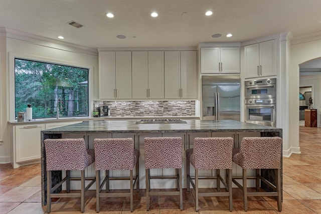 134 Trinity Oaks Ct, The Woodlands, TX 77381 - kitchen featuring appliances with stainless steel finishes, recessed lighting, a kitchen island, decorative backsplash, and dark stone countertops