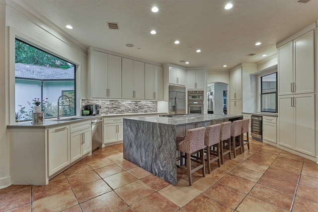134 Trinity Oaks Ct, The Woodlands, TX 77381 - kitchen with stainless steel appliances, beverage cooler, arched walkways, a center island, and recessed lighting