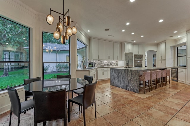 134 Trinity Oaks Ct, The Woodlands, TX 77381 - dining area with beverage cooler, a chandelier, crown molding, recessed lighting, and arched walkways