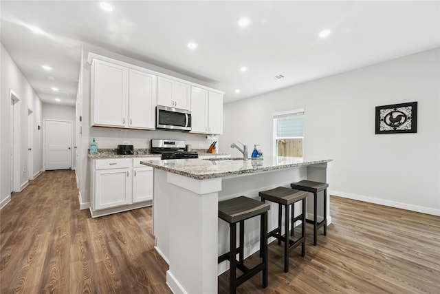 16934 Needlepoint Dr, Conroe, TX 77302 - kitchen with stainless steel appliances, dark wood-style flooring, a breakfast bar, recessed lighting, and white cabinets