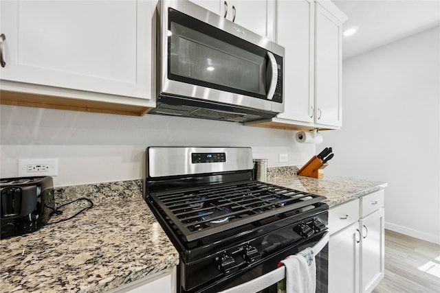 16934 Needlepoint Dr, Conroe, TX 77302 - kitchen with stainless steel appliances, white cabinetry, light stone countertops, light wood finished floors, and recessed lighting