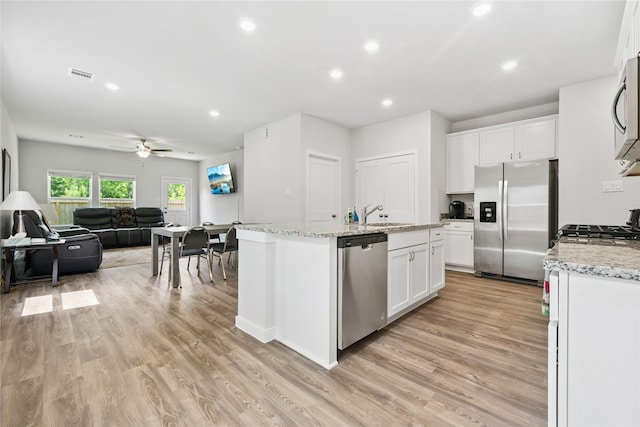 16934 Needlepoint Dr, Conroe, TX 77302 - kitchen with appliances with stainless steel finishes, open floor plan, an island with sink, white cabinetry, and light wood-style floors