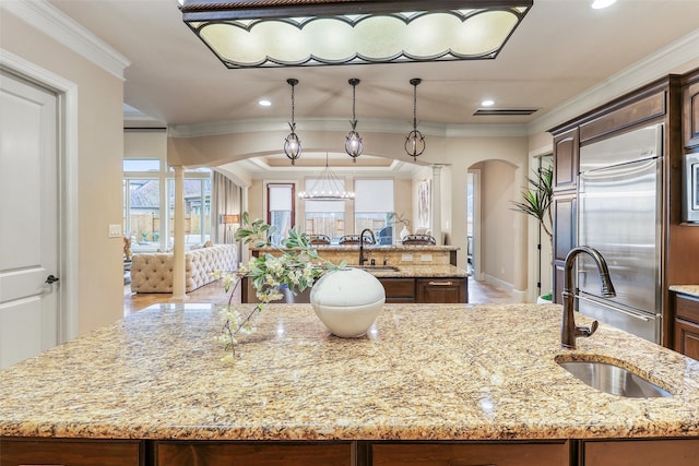 24115 Porte Toscana Ln, Richmond, TX 77406 - kitchen with an island with sink, built in fridge, arched walkways, crown molding, and light stone counters