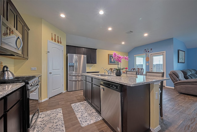 22618 Cremona Village Trl, Katy, TX 77449 - kitchen featuring stainless steel appliances, open floor plan, a kitchen bar, wood finished floors, and a kitchen island with sink
